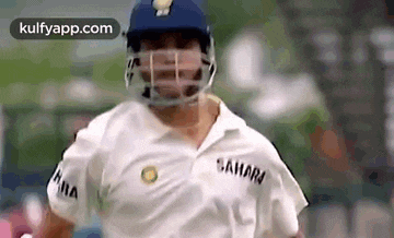 a cricket player wearing a helmet and a white shirt is running .