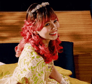 a woman with red hair and a tiara on her head smiles