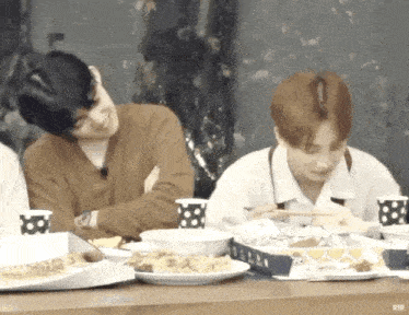 a group of young men are sitting at a table eating food .