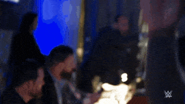 a man in a suit is shaking hands with another man in a blue hat in a room .