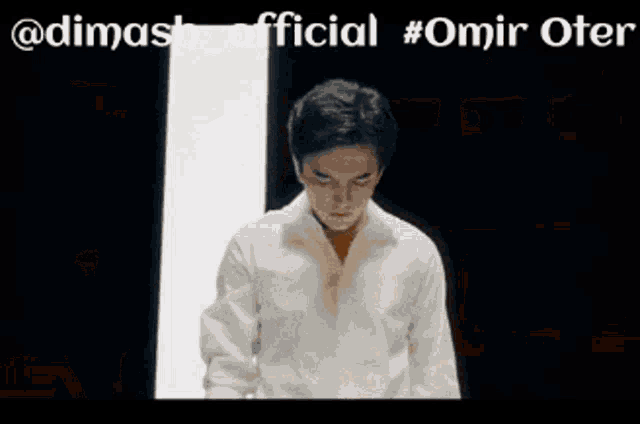 a man in a suit stands in front of a blurred background with the words " @dimash_official #omir oter "