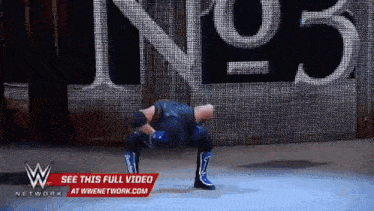 a wrestler is doing a handstand in front of a sign that says kings