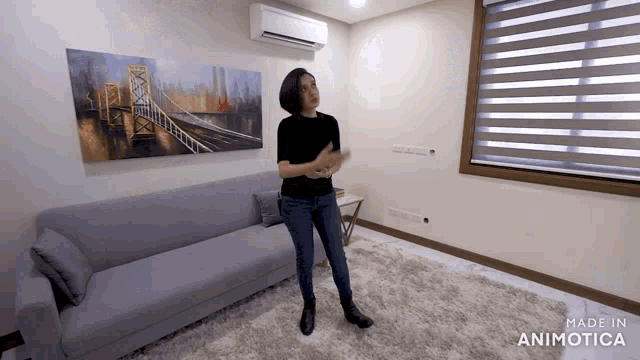 a woman is standing in a living room with a couch and a painting on the wall that says made in animotica