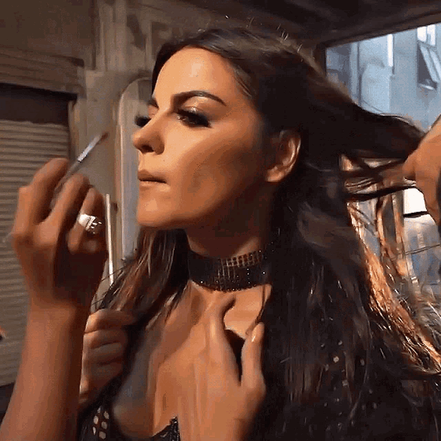 a woman wearing a choker and a ring is getting her hair done