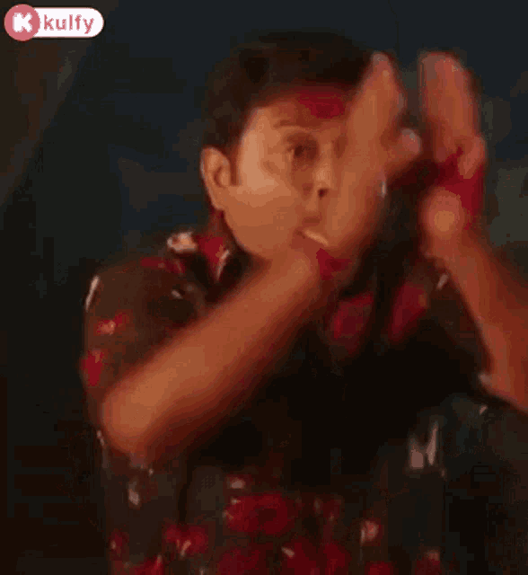 a man in a red shirt is making a funny face with his hands in the air .