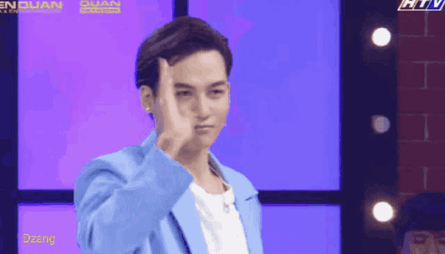 a man in a blue jacket stands in front of a purple background with htv written on it