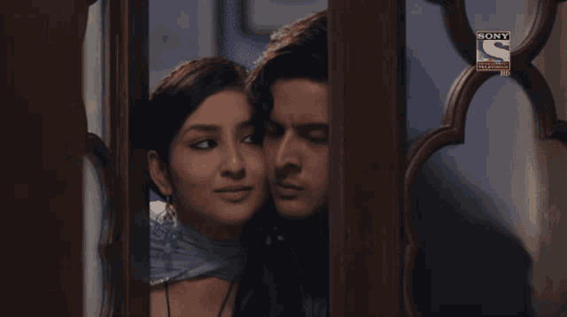 a man and a woman are looking through a window with a sony television logo on the bottom right