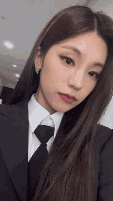 a woman in a suit and tie is taking a selfie