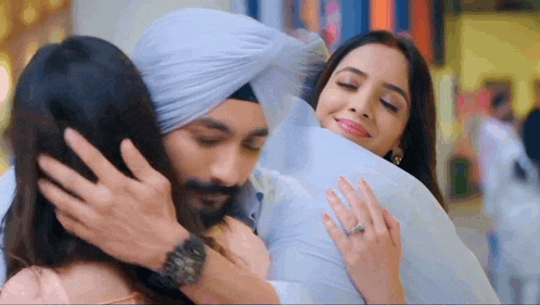a man in a turban is hugging a woman in a pink dress .