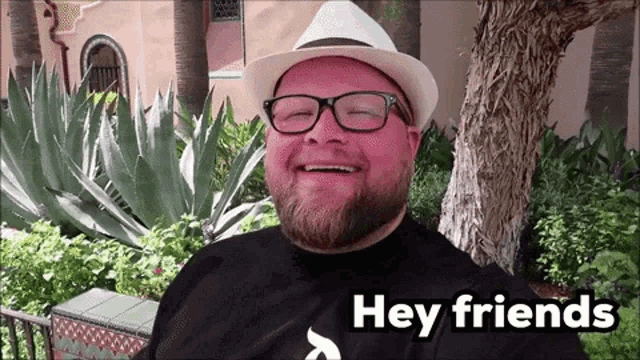 a man wearing a hat and glasses is smiling and says hey friends