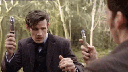 a man in a suit and bow tie is holding a pair of sonic screwdrivers in his hands .