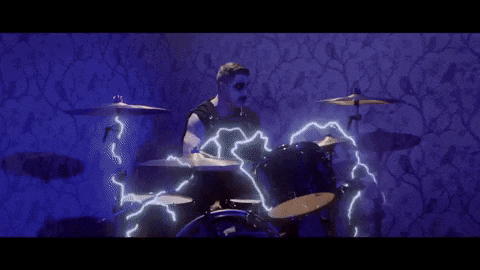 a man is playing drums in a dark room with lightning coming out of it