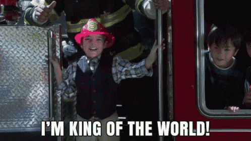 a young boy wearing a fireman 's helmet says i 'm king of the world
