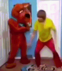 a man in a yellow shirt is standing next to a red teddy bear in a room .