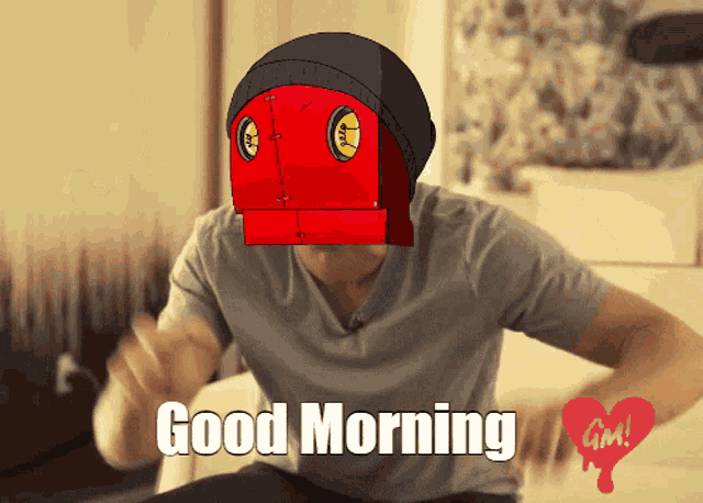 a man sitting on a bed with a red robot on his head and the words good morning on the bottom