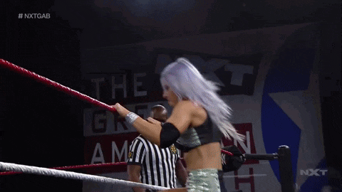 a woman is kneeling down in a wrestling ring with a rope .
