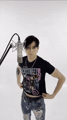 a man wearing a black t-shirt that says " backstreets " is standing in front of a microphone