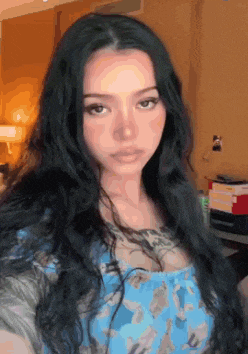 a woman with long black hair is taking a selfie in a blue dress .