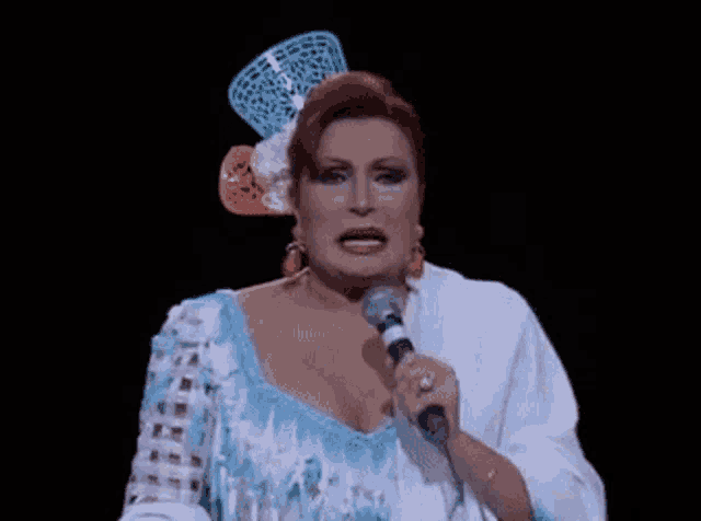 a woman in a blue and white dress is singing into a microphone on a stage .