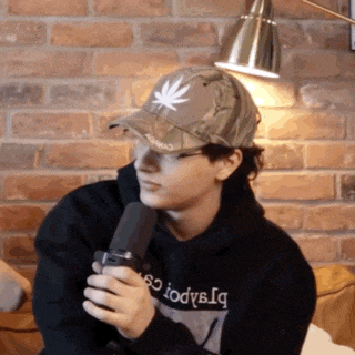 a man wearing a hat with a leaf on it is holding a microphone