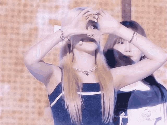 a woman making a heart shape with her hands behind her face
