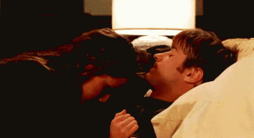 a man and a woman are kissing while laying in bed