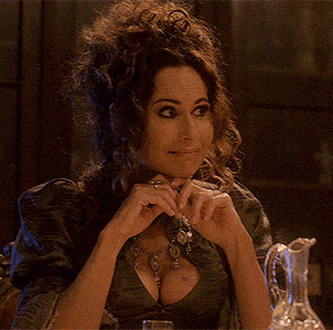 a woman sitting at a table with a necklace on her chest