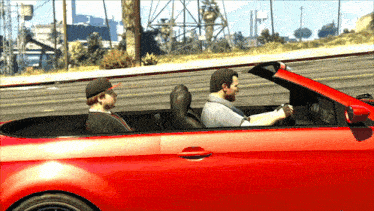 two men are sitting in a red convertible car talking to each other