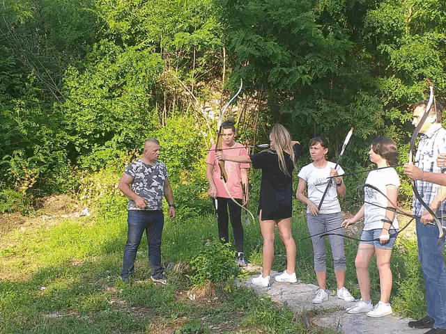 a group of people are standing in the grass holding bows