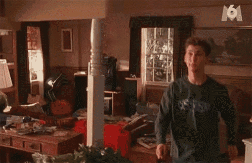 a man wearing a sweatshirt that says boston is standing in a messy living room