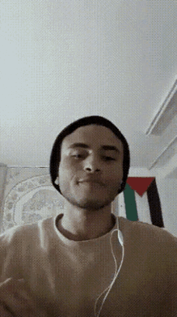 a man wearing headphones and a beanie is making a funny face .