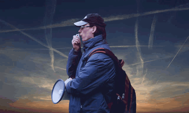 a man is holding a megaphone and wearing a hat that says ' nike ' on it