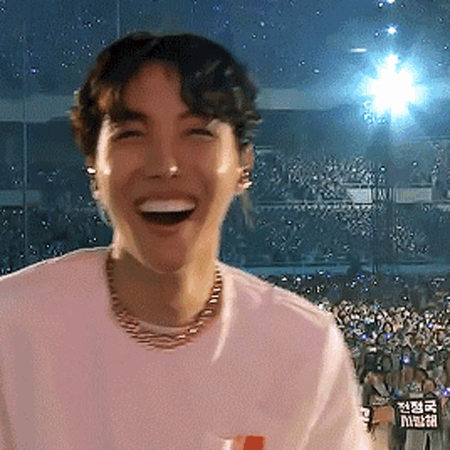 a man in a white shirt is laughing in front of a crowd with a sign that says ' a ' on it