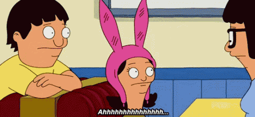 a cartoon character wearing a pink bunny hat is sitting at a table with two other people .