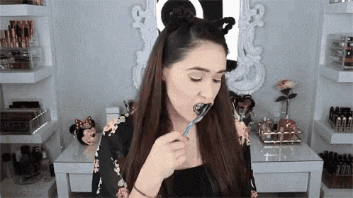 a woman is brushing her teeth with a toothbrush in a bathroom .