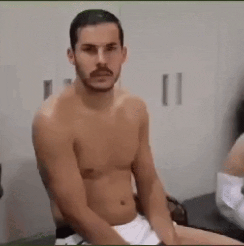 a shirtless man with a mustache is sitting on a chair in a locker room .