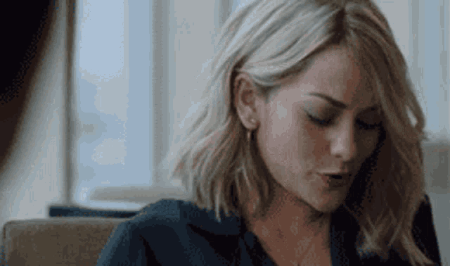 a woman with blonde hair and earrings is sitting in a chair .