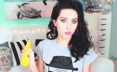 a woman wearing a gray shirt with a picture of a man on it holds a spray bottle