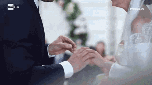 a man putting a wedding ring on a woman 's finger with rai 1 hd written on the bottom
