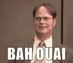 a man in a suit and tie is standing in front of a sign that says bah quai .