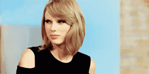 taylor swift is wearing a black dress and looking at the camera .