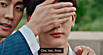 a man is covering another man 's eyes with his hands while another man looks on .