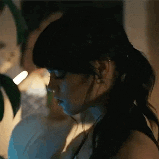 a woman in a ponytail is looking down at something in the dark .