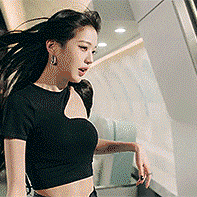 a woman in a black crop top is standing in front of a wall .