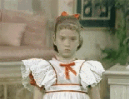 a little girl in a white dress with a red bow on her head .