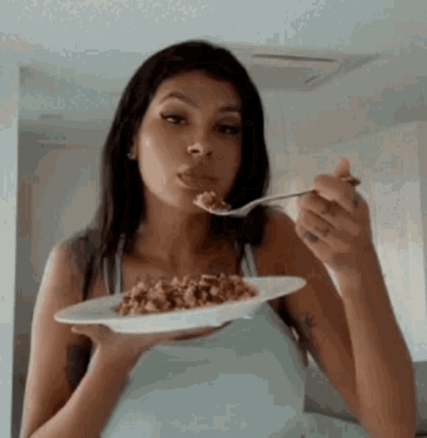 a woman is eating food from a plate with a spoon .