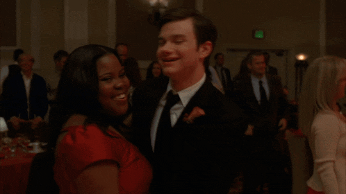 a man in a suit and tie is dancing with a woman in a red top