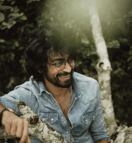 a man with glasses and a beard is smiling