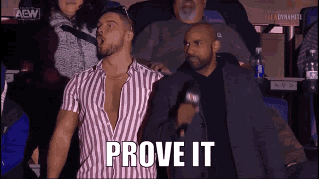 a man in a striped shirt stands next to a man in a suit with the words prove it written on the screen