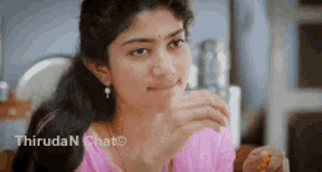 a woman in a pink shirt is eating a piece of food